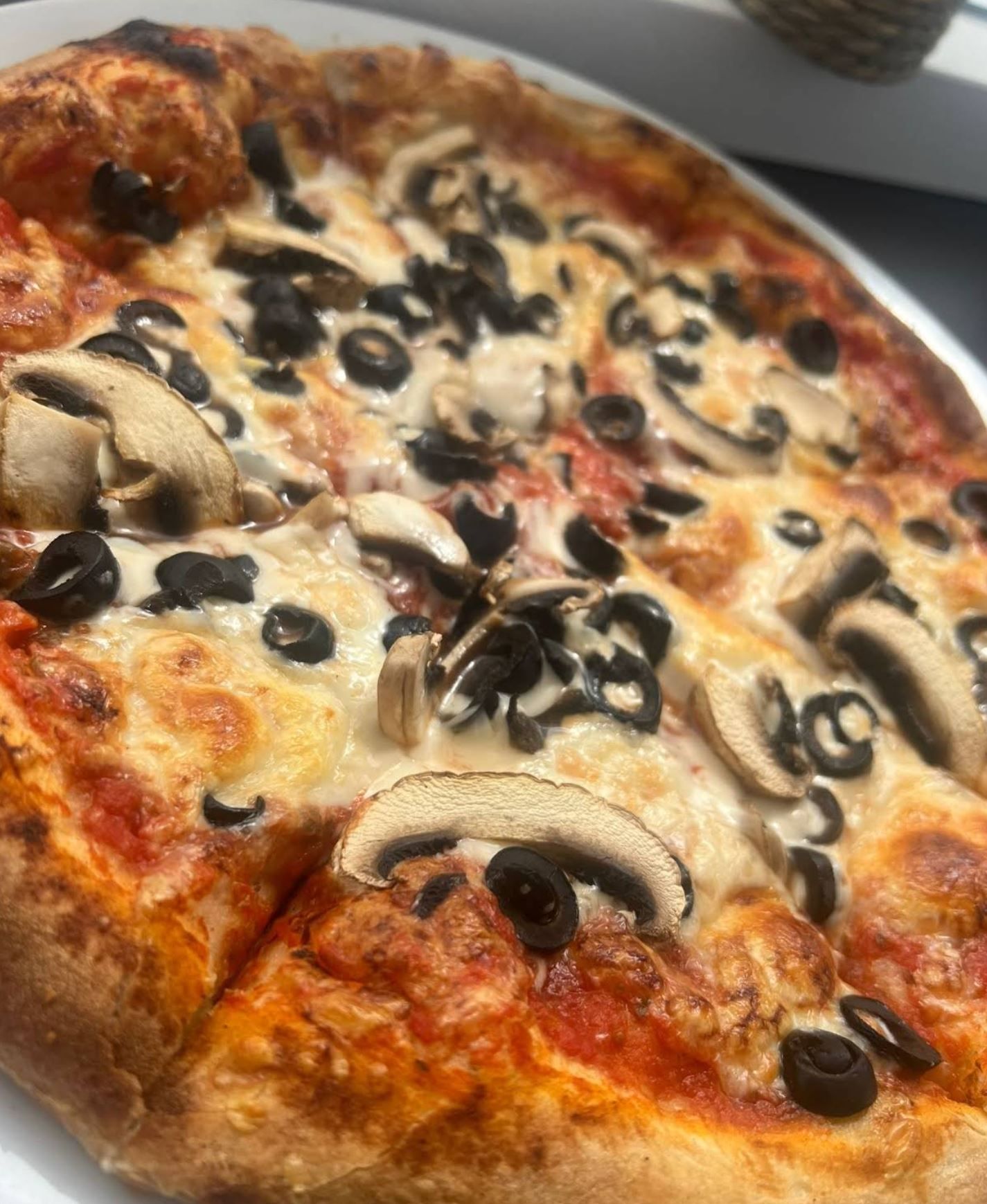 Frisch gebackene Pizza mit Champignons und Oliven aus dem Ofen von Da Giuseppe